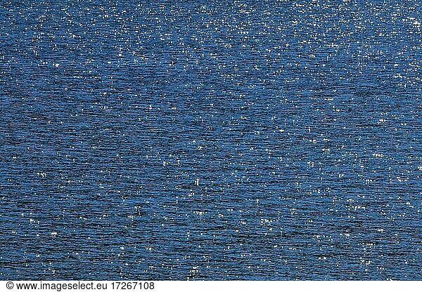 Sunbeams reflect glittering on the water surface of the Vierwaldstättersee and form an abstract pattern