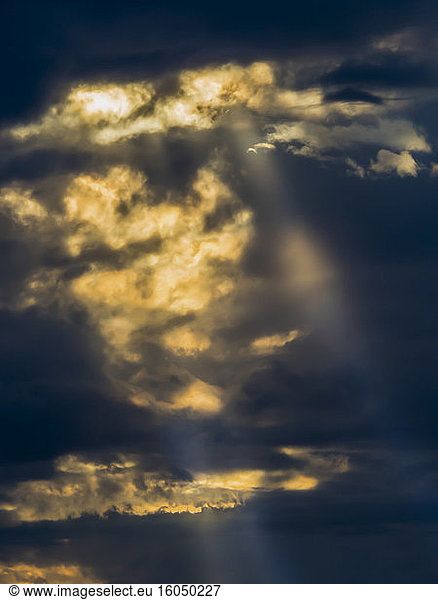 Sunlight piercing through dark storm clouds