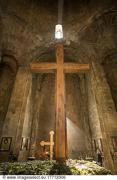 Sunlight streams into Jvari Monastery over a cross  as a woman prays in front of a saint's picture; Mtskheta  Georgiaq