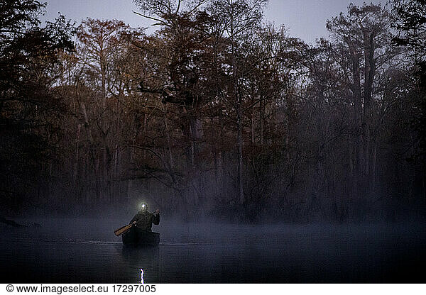 Sunrise canoe ride on foggy river.
