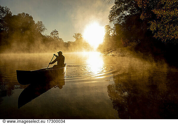 Sunrise canoe ride on foggy river.