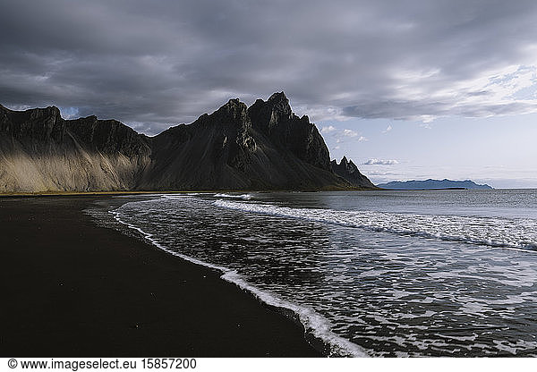 Sunrise on dramatic beach in Iceland surrounded by mountains