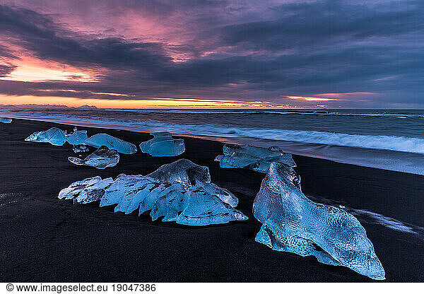 Sunset  black sand beach and chunks of ice in Iceland