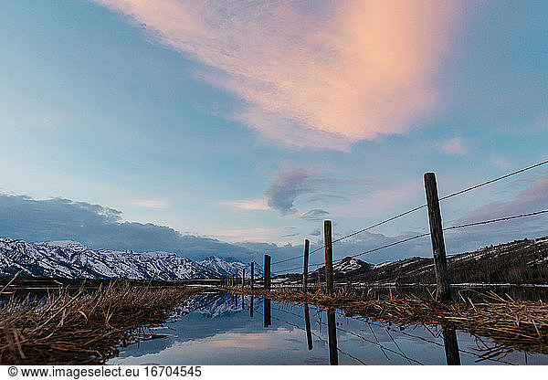 sunset cloud colors reflect over a flooded Wyoming Teton ranch