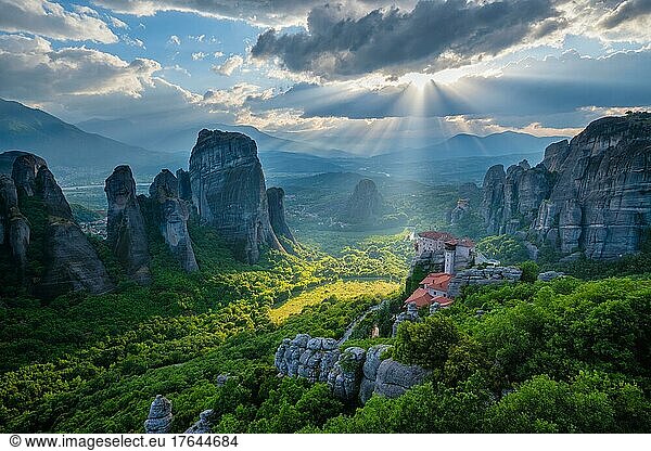 Sunset over monastery of Rousanou and Monastery of St. Nicholas Anapavsa in famous greek tourist destination Meteora in Greece on sunset with sun rays and lens flare and dramatic sky