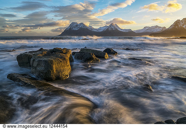 Sunset over the mountains of the Strandir Coast  Iceland as the surf pounds the shoreline  West Fjords  Iceland