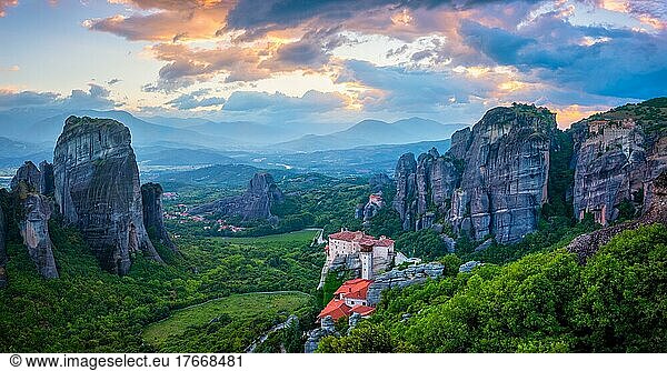Sunset sky and monastery of Rousanou and Monastery of St  Nicholas Anapavsa in famous greek tourist destination Meteora in Greece with sun rays and lens flare