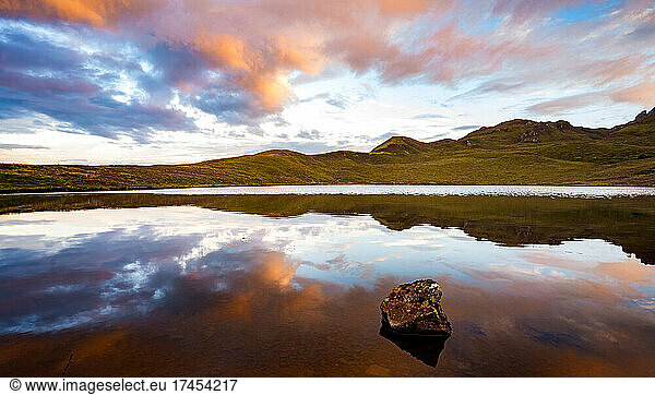Sunset sky reflection in mirror lake Scotland with heather hills