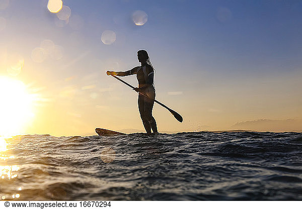SUP-Surferin bei Sonnenuntergang