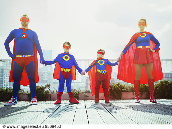 Superhero family holding hands on city rooftop