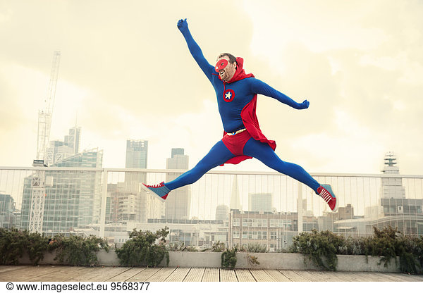 Superhero jumping on city rooftop