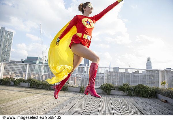 Superhero jumping on city rooftop