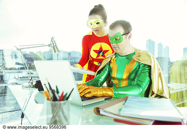 Superheroes working with laptop in office