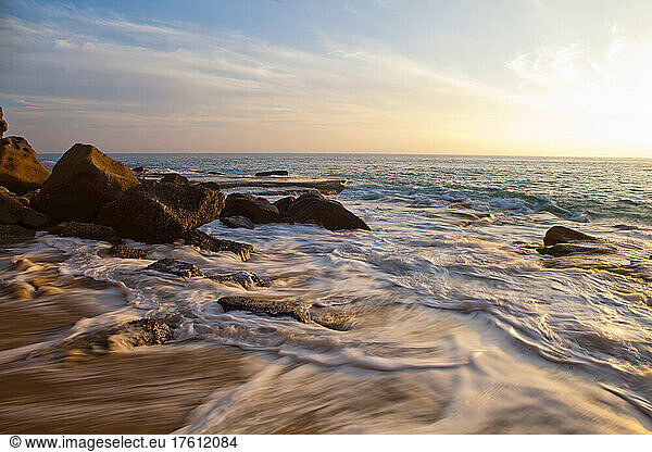 Surf washing up on sand at sunset along the California coastline at Laguna Beach; Laguna Beach  California  United States of America