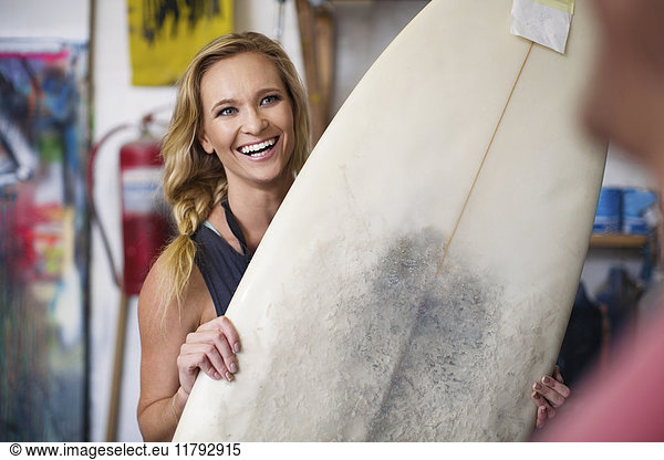 Surfboard shaper workshop  female employee smiling with surfboard