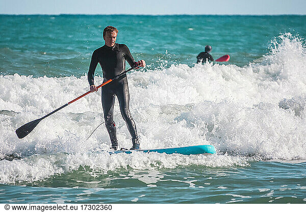 Surfer auf der Welle auf einem Paddle-Surfbrett in Benicasim Spanien