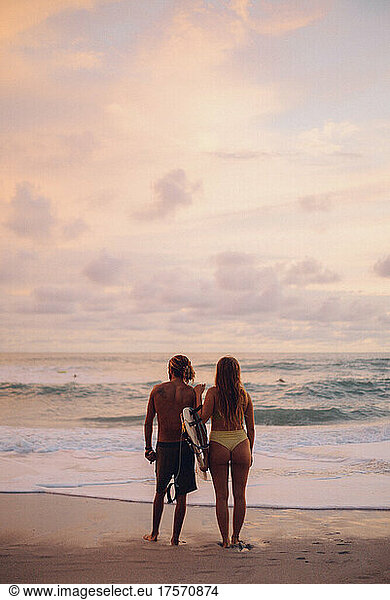 surfer couple watching the ocean before surf