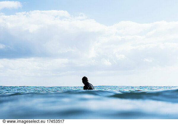 surfer waiting for wave  sitting on board  blue