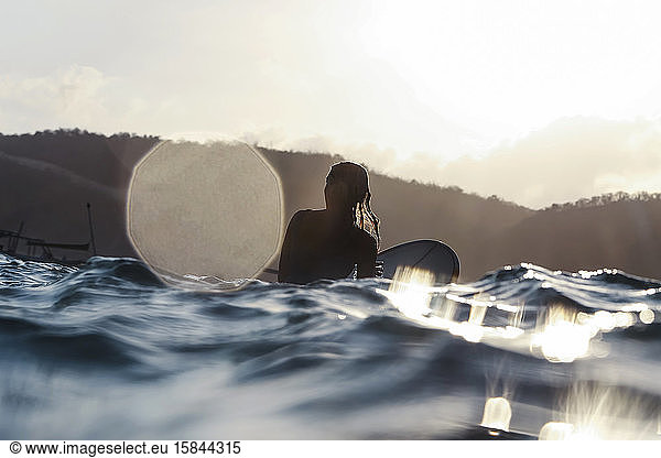 Surferin im Ozean bei Sonnenuntergang