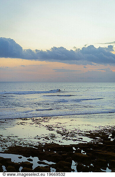 Surfers catching waves at sunset  Bali  Indonesia.