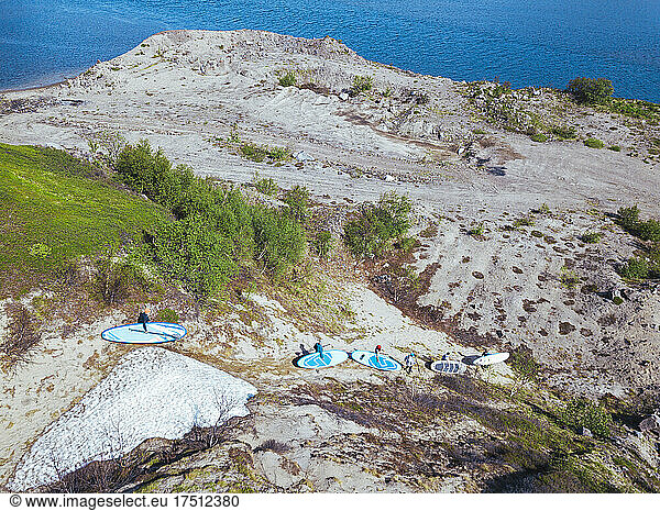 Surfers descending sandy hill toward bank of Teriberka River