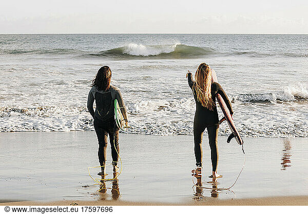Surfers looking at sea holding surfboards at beach  Gran Canaria  Canary Islands