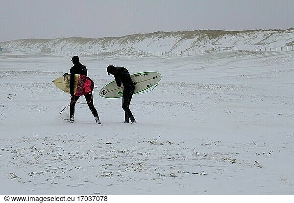 Surfers walking in the snow at the beach of Den Haag  Holland