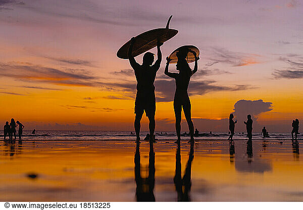 Surfers with surfboards at sunset  Bali.