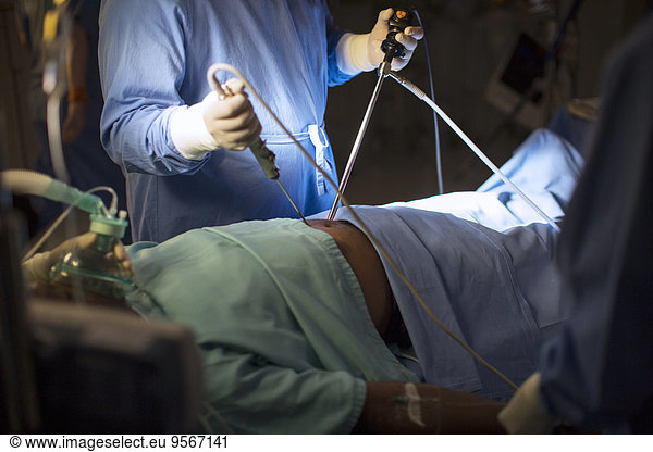 Surgeon holding medical tools and performing laparoscopic surgery in operating theater