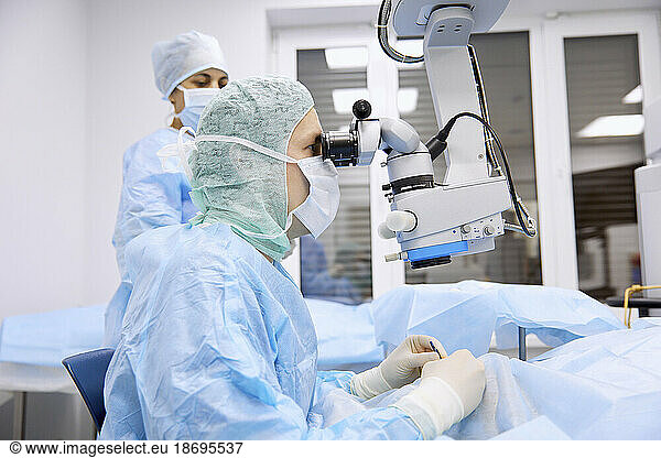 Surgeon performing eye surgery with microscope in operating room