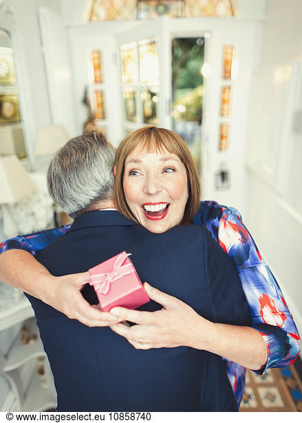Surprise mature woman receiving gift from husband