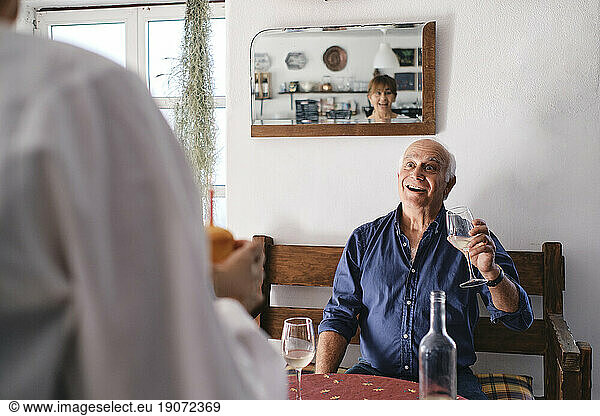 Surprised senior man holding wine glass and looking at woman with cupcake
