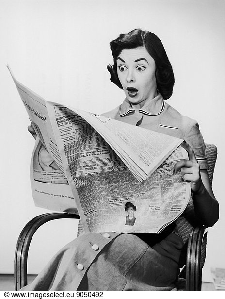 Surprised woman reading newspaper