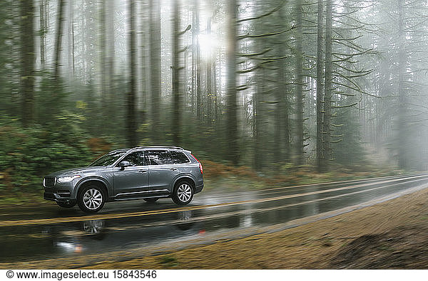 SUV automobile driving through foggy and rainy forest road