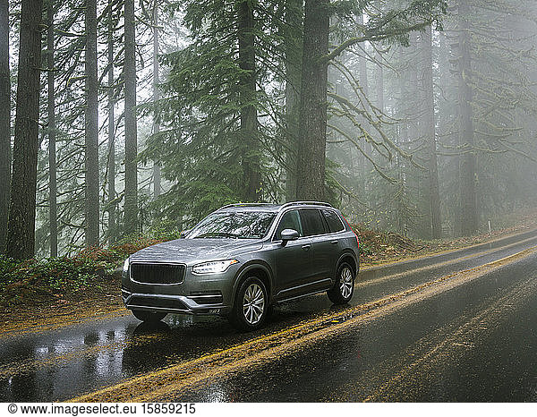 SUV automobile driving through foggy and rainy forest road
