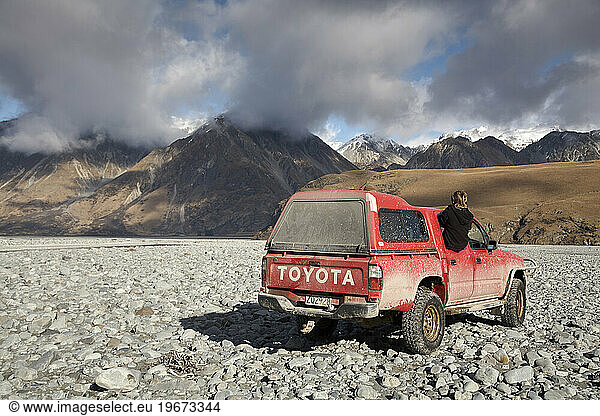 SUV driving on rocks with mountains in background  New Zealand