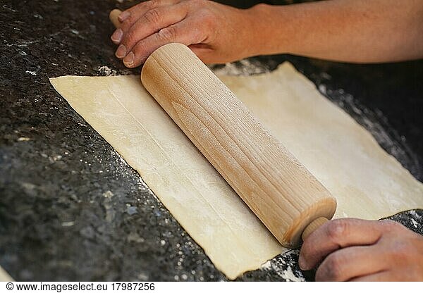 Swabian cuisine  preparation of Reutlinger Schiedwecken  rolling out puff pastry  rolling pin  men's hands  puff pastry with veal filling  hearty pie  baking  traditional Swabian dish  studio shot  food photography  Germany  Europe