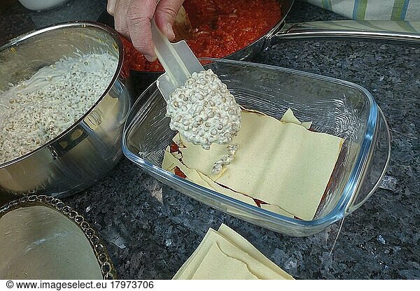 Swabian cuisine  preparing alblinsen casserole  filling lentils with sour cream in casserole dish  pasta dough  pasta patties  lasagne  baking dish  traditional cuisine  hearty oven dish  main dish  man's hand  dough scraper  kitchen scraper  studio  food photography  Germany  Europe