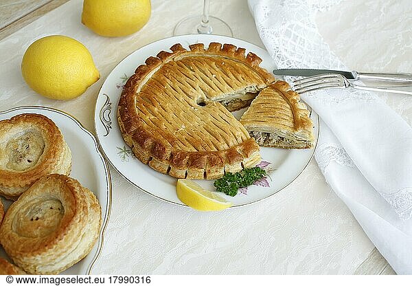 Swabian cuisine  Reutlinger Schiedwecken  puff pastry with veal filling  hearty pâté on plate  cutlery  knife  fork  lemons  parsley  bake  traditional Swabian dish  studio shot  food photography  Germany  Europe