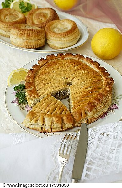 Swabian cuisine  Reutlinger Schiedwecken  puff pastry with veal filling  hearty pie on plate  cutlery  knife  fork  lemons  parsley  bake  traditional Swabian dish  studio shot  food photography  Germany  Europe