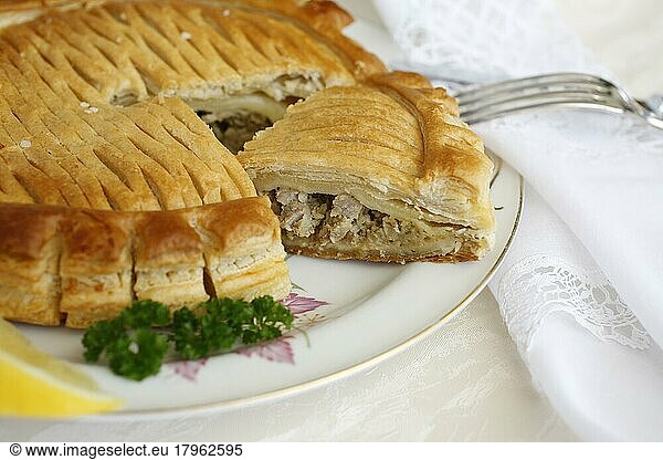 Swabian cuisine  Reutlinger Schiedwecken  puff pastry with veal filling  hearty pie on plate  fork  parsley  bake  traditional Swabian dish  studio shot  food photography  Germany  Europe