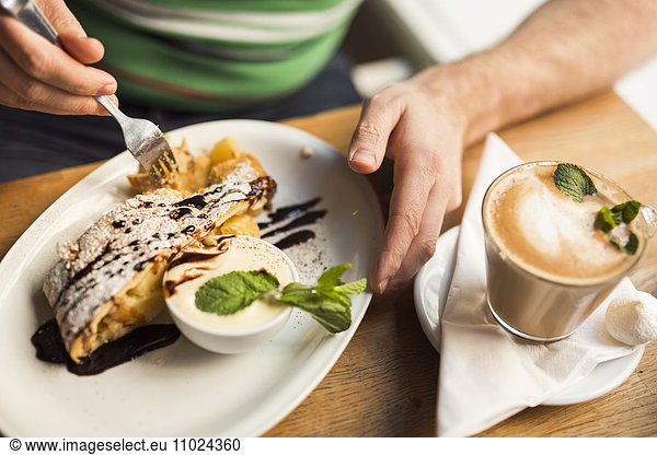 Sweden  Stockholm  Gamla Stan  Man having dessert and coffee in cafe  close up of hands