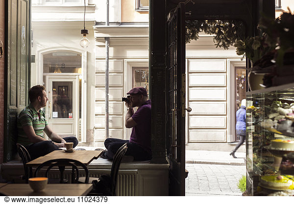 Sweden  Stockholm  Gamla Stan  Man photographing friend in coffee shop