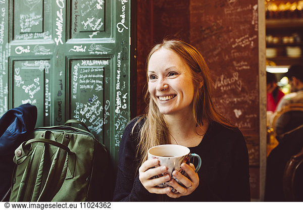Sweden  Stockholm  Gamla Stan  Smiling woman holding coffee cup in cafe