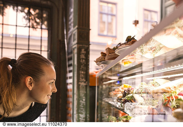 Sweden  Stockholm  Gamla Stan  Smiling woman looking at display in cafe