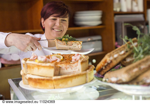 Sweden  Stockholm  Gamla Stan  Smiling woman serving tart in cafe