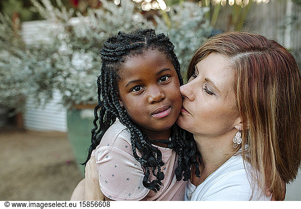 Sweet black daughter and loving white mom hugging