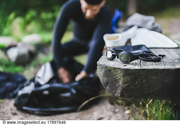 Swimming goggles and diving flippers on wooden bench