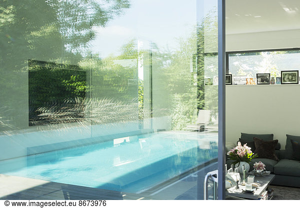Swimming pool reflected in glass windows of modern house