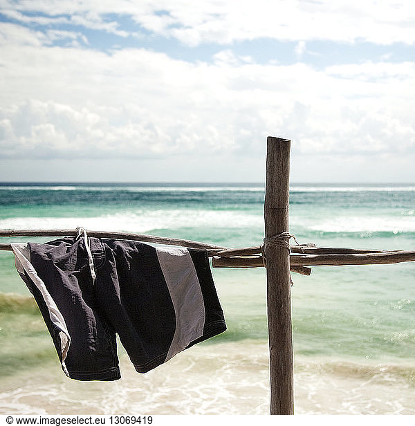 Swimming trunks drying on wooden railing against sea